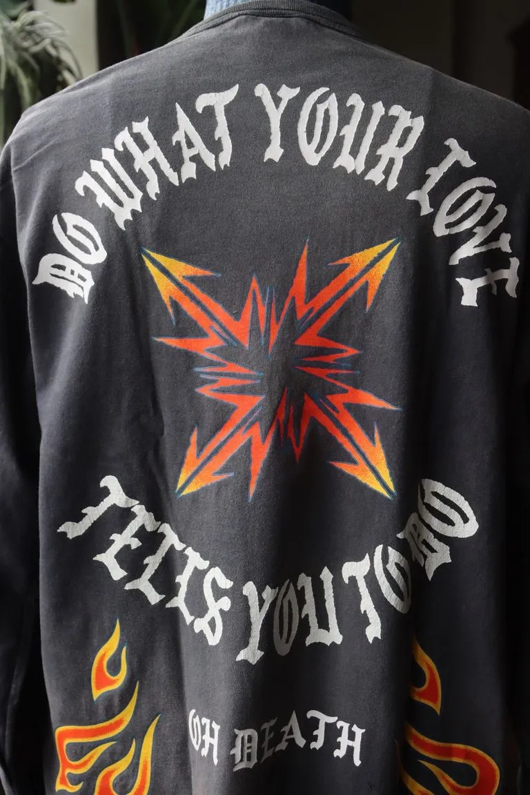 SAINT Mxxxxxx M/AFTER LS_TEE/BLACK Flame arrow Letter M retro distressed long tee Washed black S-XL Tubular fabric Assute ready-made garments dyed The whole piece is sprayed with horse-hair spray and then sprayed again to fade the color. The collar and cuffs are frayed. Many places are frayed. Extra large printing position. Very difficult to print. Complete accessories. With little angel anti-counterfeiting label.